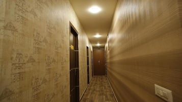 Un couloir aux murs ornés de motifs, doté d’un plancher en bois et de portes donnant accès aux différentes pièces.