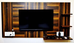 Televisor de pantalla plana montado en una pared de madera, con un estante debajo.