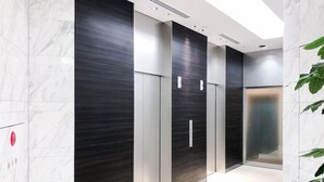 A modern elevator area with marble walls and a sleek design. - UNIZO INN Hiroshima Ekimae (Hiroshima)