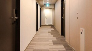 A hallway with a wooden floor, beige walls, and doors on both sides. - UNIZO INN Hiroshima Ekimae (Hiroshima)