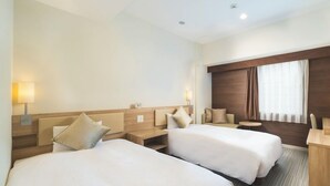 A hotel room with two beds, a desk, a chair, a lamp, and a window with curtains. - UNIZO INN Hiroshima Ekimae (Hiroshima)