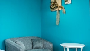 Una habitación con una pared verde azulado, un sofá gris y una pequeña mesa blanca.