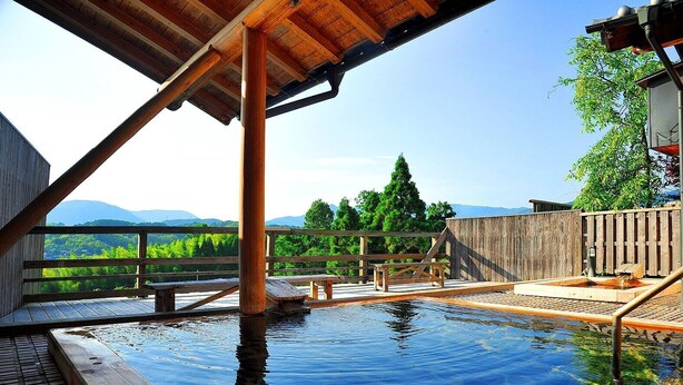 A hot spring area with wooden deck and railings, surrounded by trees and mountains. - Kafutei (Yamaga)