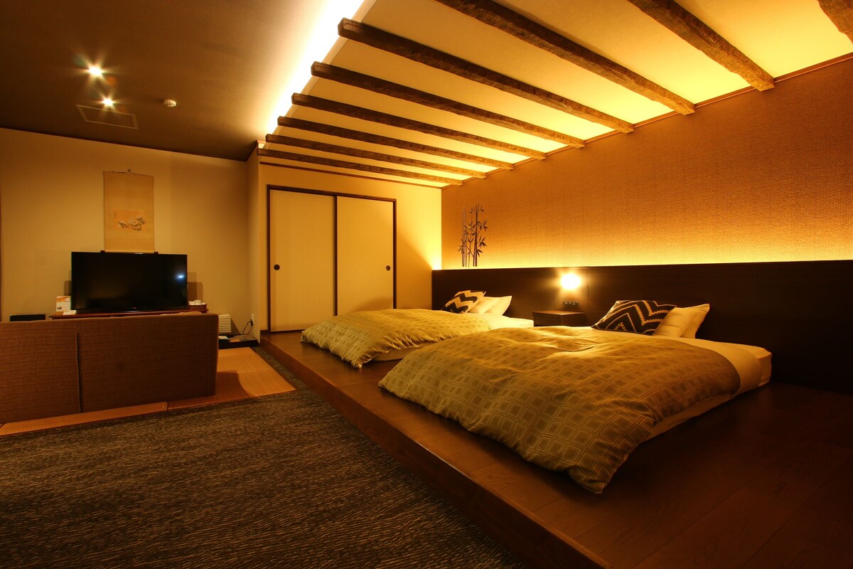 Une chambre à coucher avec un lit, une table de chevet et un téléviseur posé sur un meuble.