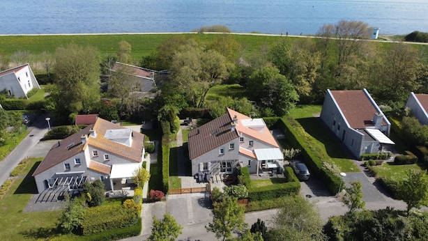 An aerial view of a residential area with houses, a pathway, and a body of water.