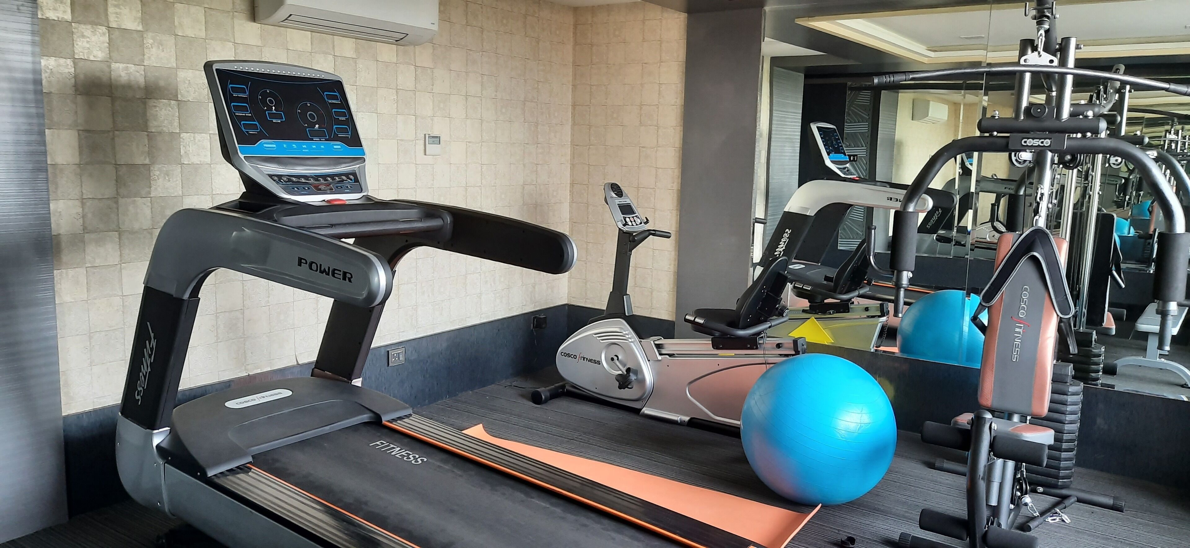 A gym with a treadmill, elliptical, and exercise ball.