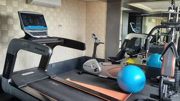 A gym with a treadmill, elliptical, and exercise ball.