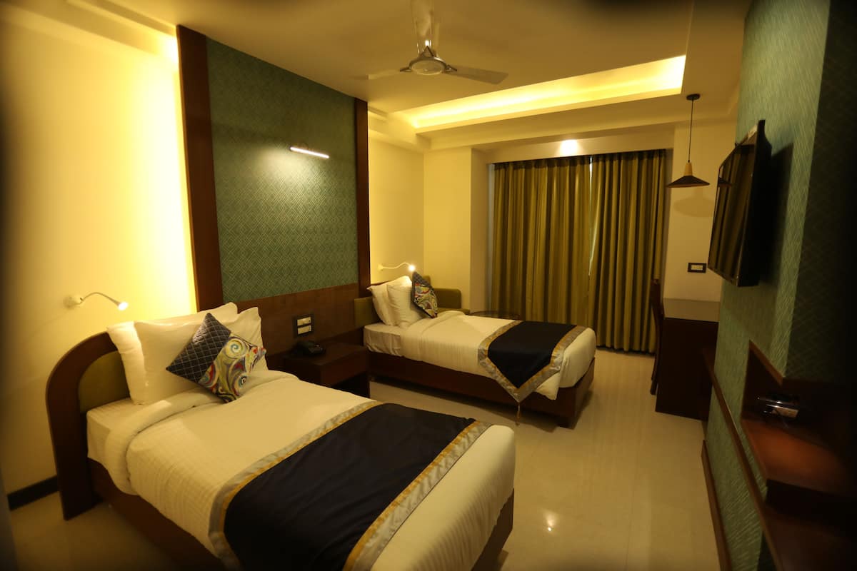 A hotel room with two beds, a ceiling fan, a TV, and a large window with curtains.