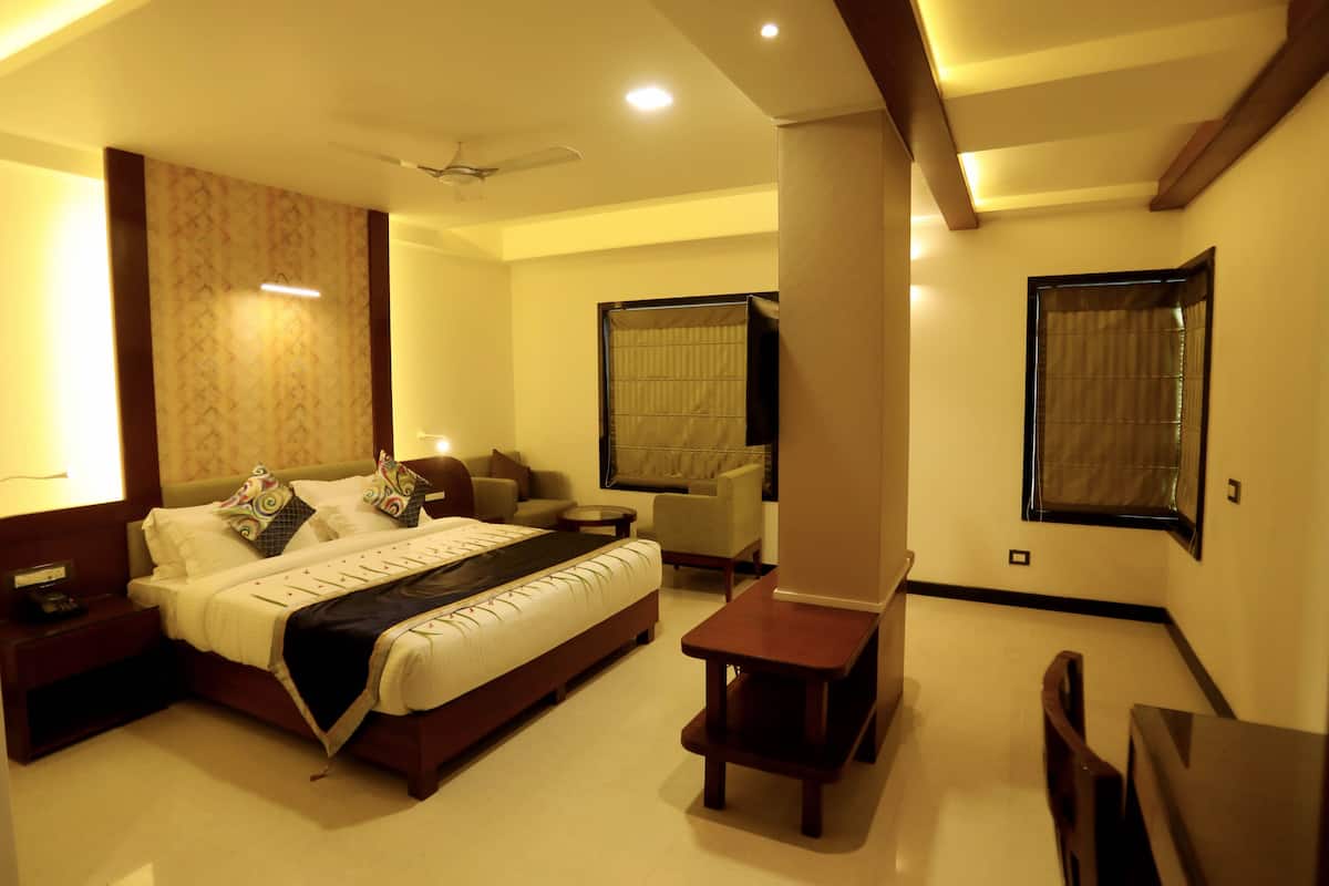 A well-lit bedroom with a bed, bedside table, and a small desk with a chair.