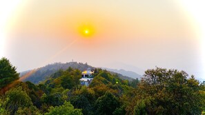 A building with a dome on top, surrounded by dense green trees, on a hill with a clear sky. - Hotel Nagarkot Inn (Baluwapati Deupur)