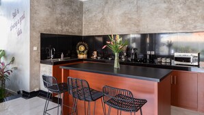 A modern kitchen with a large island, black bar stools, and a decorative wall with a quote. - Villa Four Elements (Canggu)