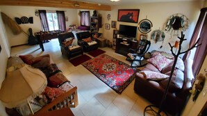 A cozy living room with a sofa, armchairs, a coffee table, and a TV. - Moondance lodge is a place you can go and relax and access the outdoors (Index)