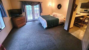 A bedroom with a bed, a dresser, a television, and a door leading to a balcony. - Moondance lodge is a place you can go and relax and access the outdoors (Index)
