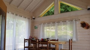 A wooden interior with a dining table and chairs, a window with curtains, and a decorative wall piece. - Vacation cottage *** - Panoramic view - Sauna - Near lake - Mountain (Saulxures-sur-Moselotte)