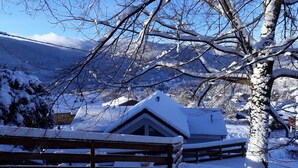 A snow-covered wooden bench and a building with a sloped roof, surrounded by bare trees and a mountain in the background. - Vacation cottage *** - Panoramic view - Sauna - Near lake - Mountain (Saulxures-sur-Moselotte)