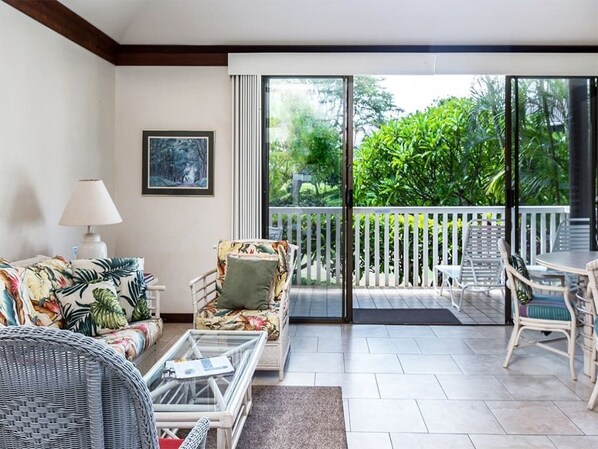 A modern living room with a sofa, a glass coffee table, and a dining area with chairs.