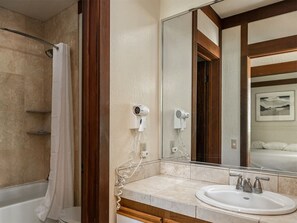 A bathroom with a bathtub, a sink, a mirror, and a shower curtain.