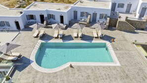 A rooftop swimming pool with lounge chairs and umbrellas, surrounded by a white building with stone accents. - Nida Mykonos (Mykonos)