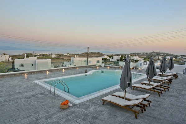 A rooftop pool with lounge chairs and umbrellas, surrounded by white buildings and a clear sky. - Nida Mykonos (Mykonos)