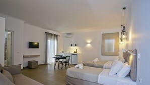 A modern hotel room with a sofa, two beds, a desk, a TV, and a kitchen area. - Nida Mykonos (Mykonos)
