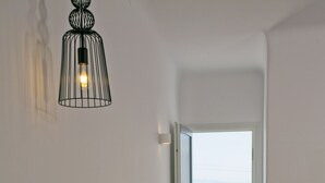 A hotel room with two beds, a view of the sea, and a balcony with a table and chairs. - Nida Mykonos (Mykonos)