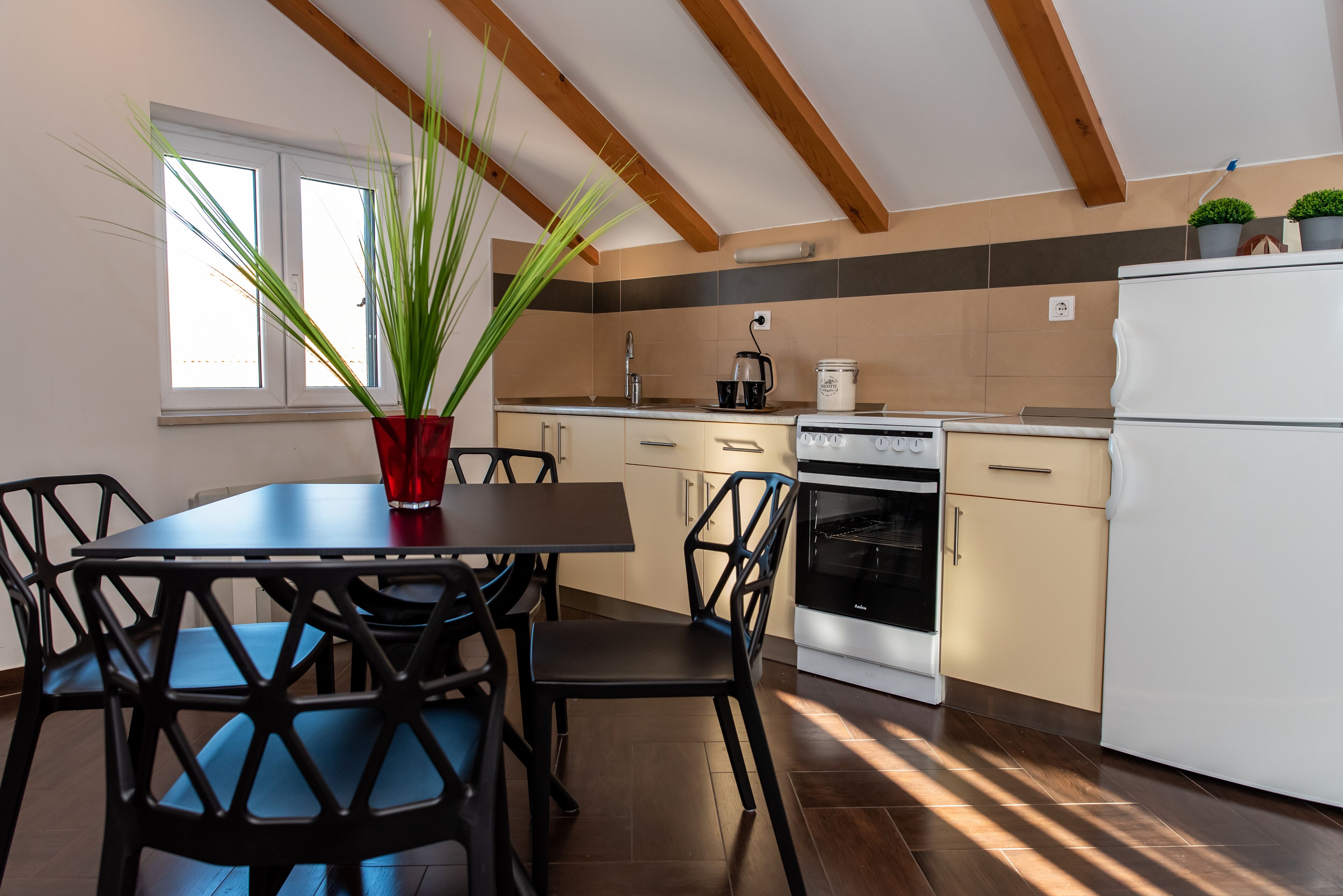 Una cocina con una mesa de comedor, sillas, una cafetera, un horno y un refrigerador.