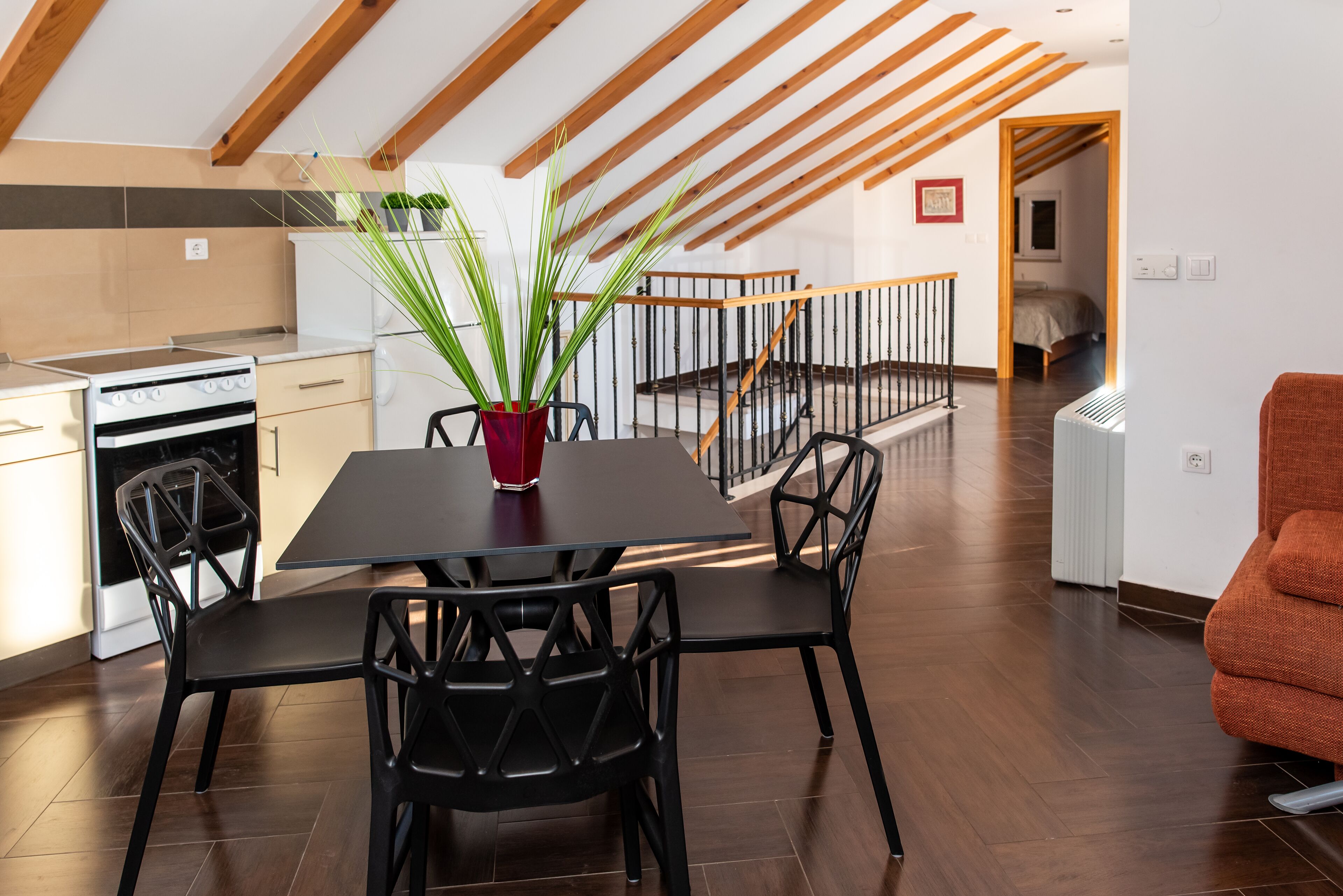 Una cocina moderna con zona de comedor, con techo de madera, una mesa de comedor con sillas y una planta en maceta.