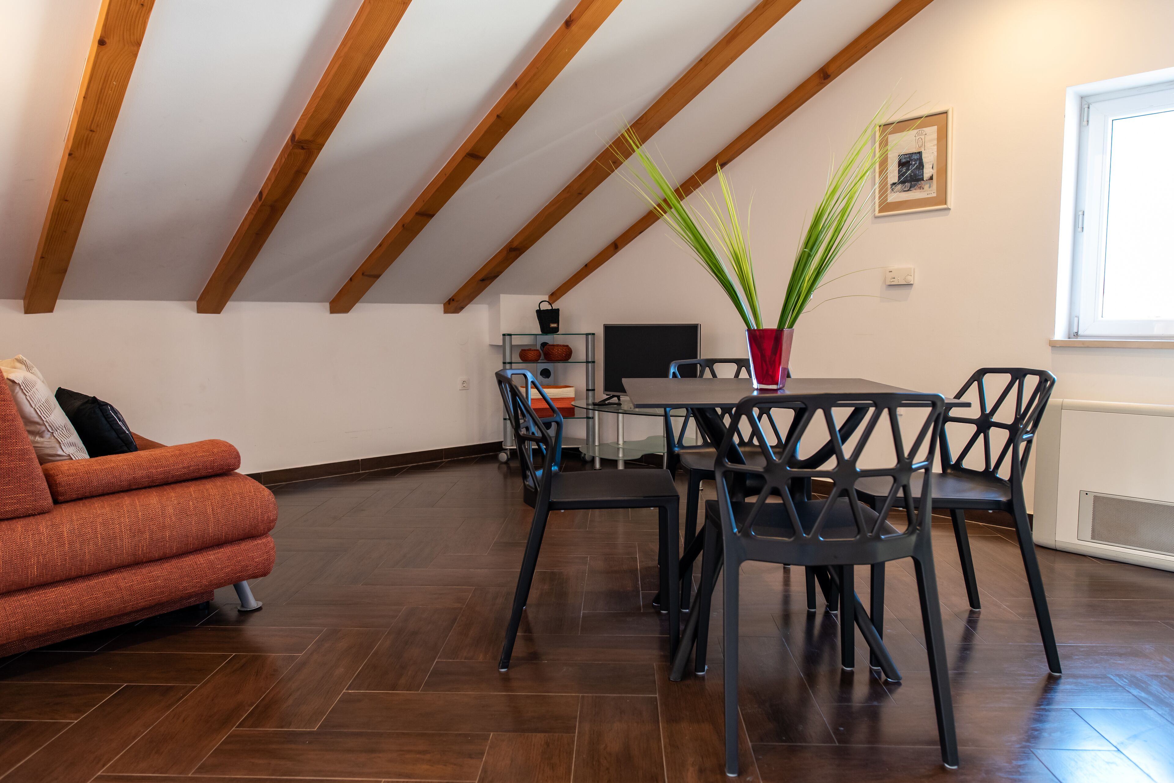 A dining area with a table and chairs, a sofa, and a potted plant.