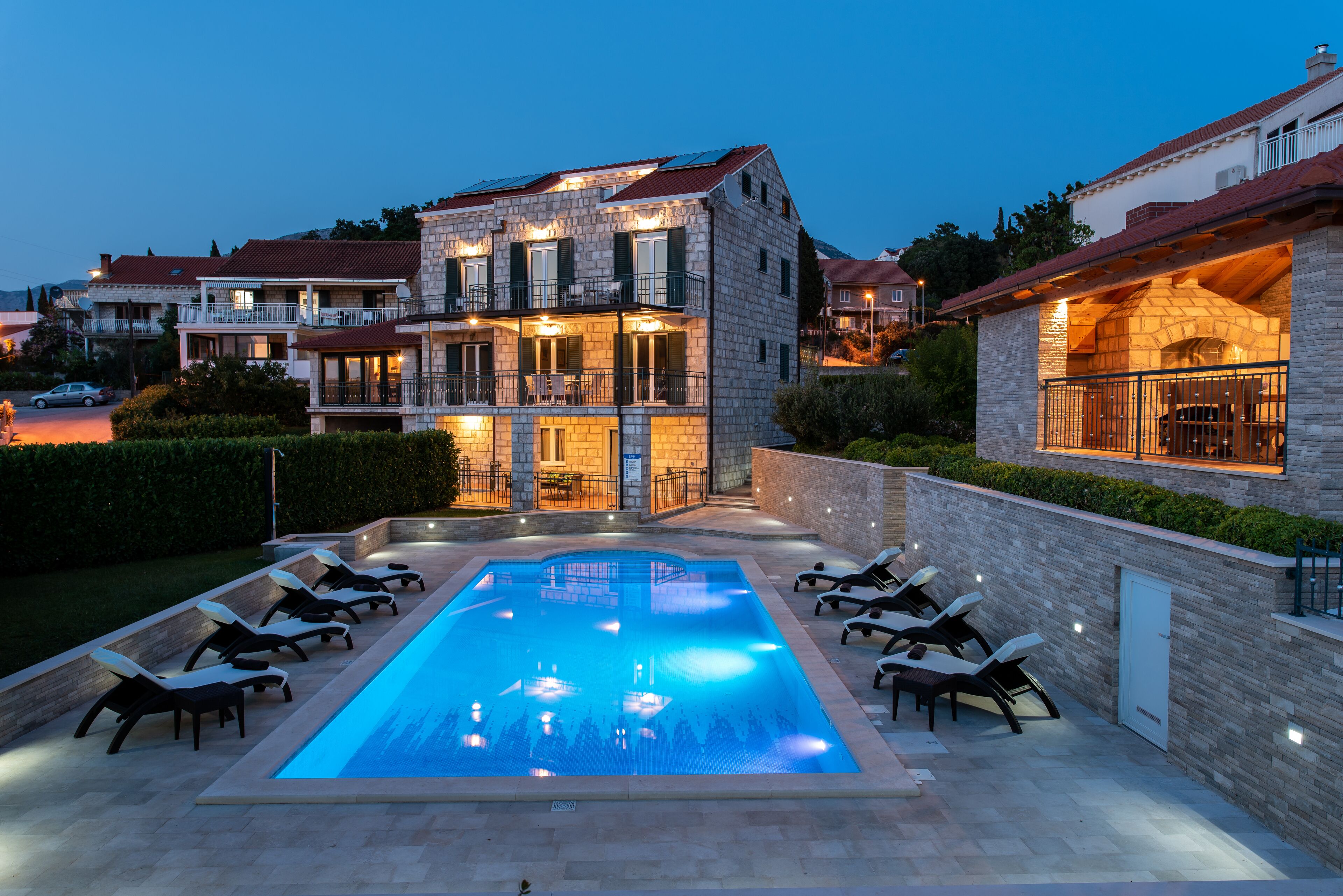 A modern house with a swimming pool, outdoor seating, and a stone facade.
