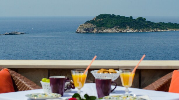 A table set with breakfast items and a view of the sea and a small island. - Apartments Sutalo (Konavle)