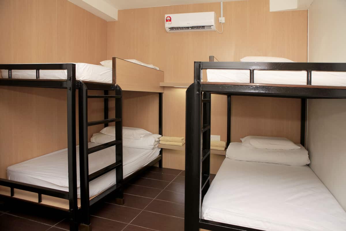 A room with three bunk beds, wooden walls, and an air conditioning unit.