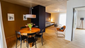 A modern living room with a wooden dining table, black chairs, a sofa, and a coffee table.