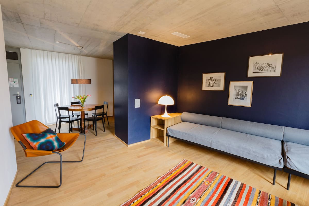 Una sala de estar moderna con un sofá, una silla, una mesa de comedor y una lámpara.