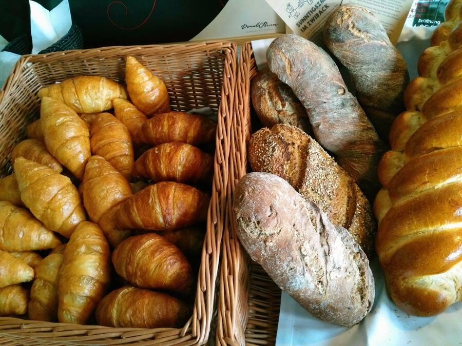A variety of breads including croissants and baguettes in wicker baskets.