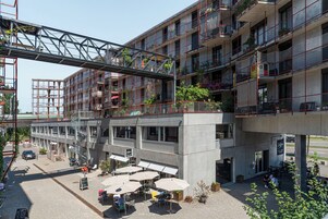 Un edificio de varios pisos con terraza al aire libre y un puente peatonal.
