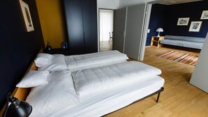 A room with a large bed, a desk, a chair, and a sofa.