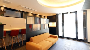A modern interior with a sofa, bar stools, and a large window. - Stay SAKURA Kyoto TSUBAKI (Kyoto)