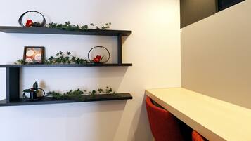A modern interior with three black shelves against a white wall, each adorned with greenery and small decorative items.