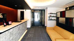 A reception area with a counter, a sofa, and a hallway leading to another room. - Stay SAKURA Kyoto TSUBAKI (Kyoto)