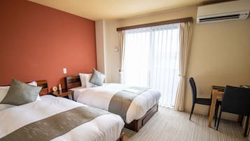A hotel room with two beds, a desk, a chair, and a window with curtains.