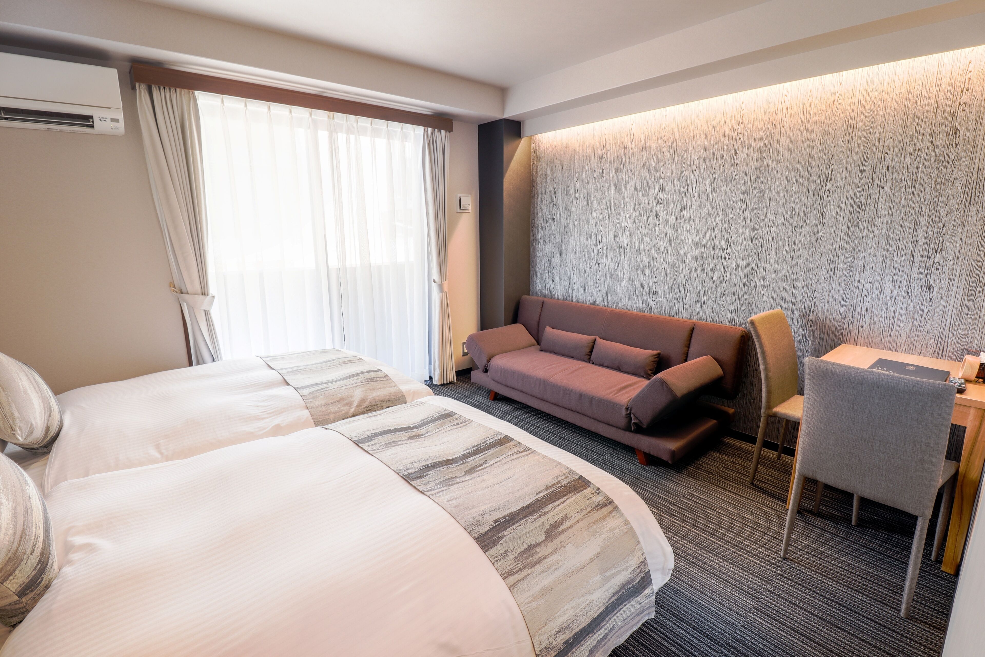 Une chambre d’hôtel avec deux lits, un canapé, un bureau et une chaise.