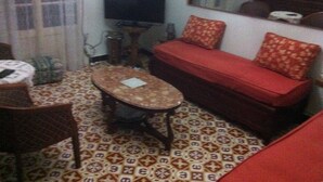 A living room with a sofa, a small table, a television, and patterned flooring.