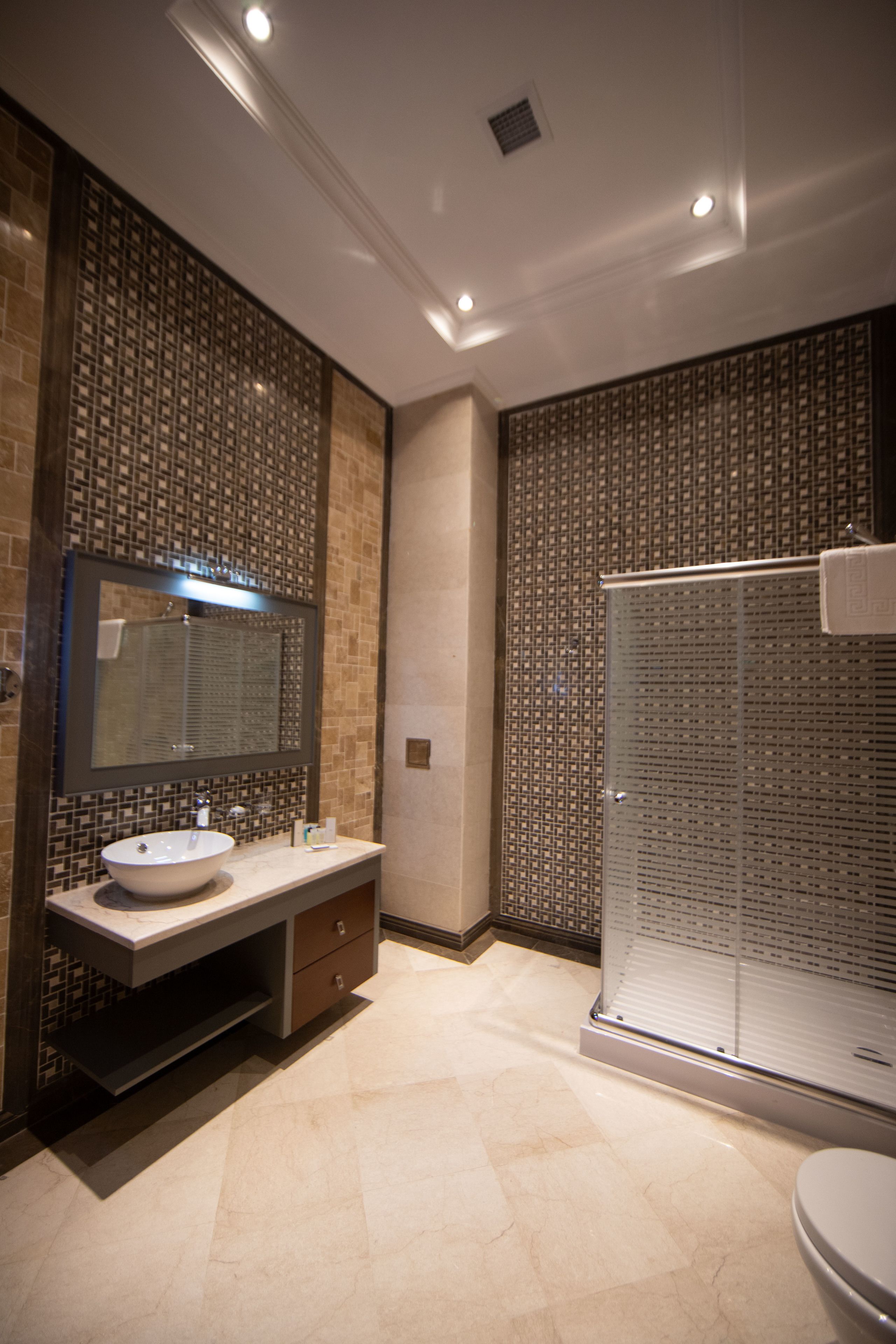A modern bathroom with a large mirror, a sink, and a shower area.
