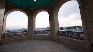 A balcony with three large arched windows overlooking a cityscape. - Saat Meydani Hotel (Nakhchivan)