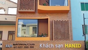 A hotel named HANID Hotel with a modern brick facade, large windows, and a contact number displayed.