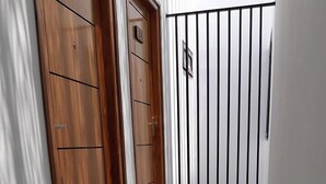 A hallway with patterned floor tiles, wooden doors, and a metal gate.