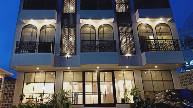 A modern two-story building with large windows and balconies, well-lit at night. - Front One Residence Syariah Mampang (Jakarta)