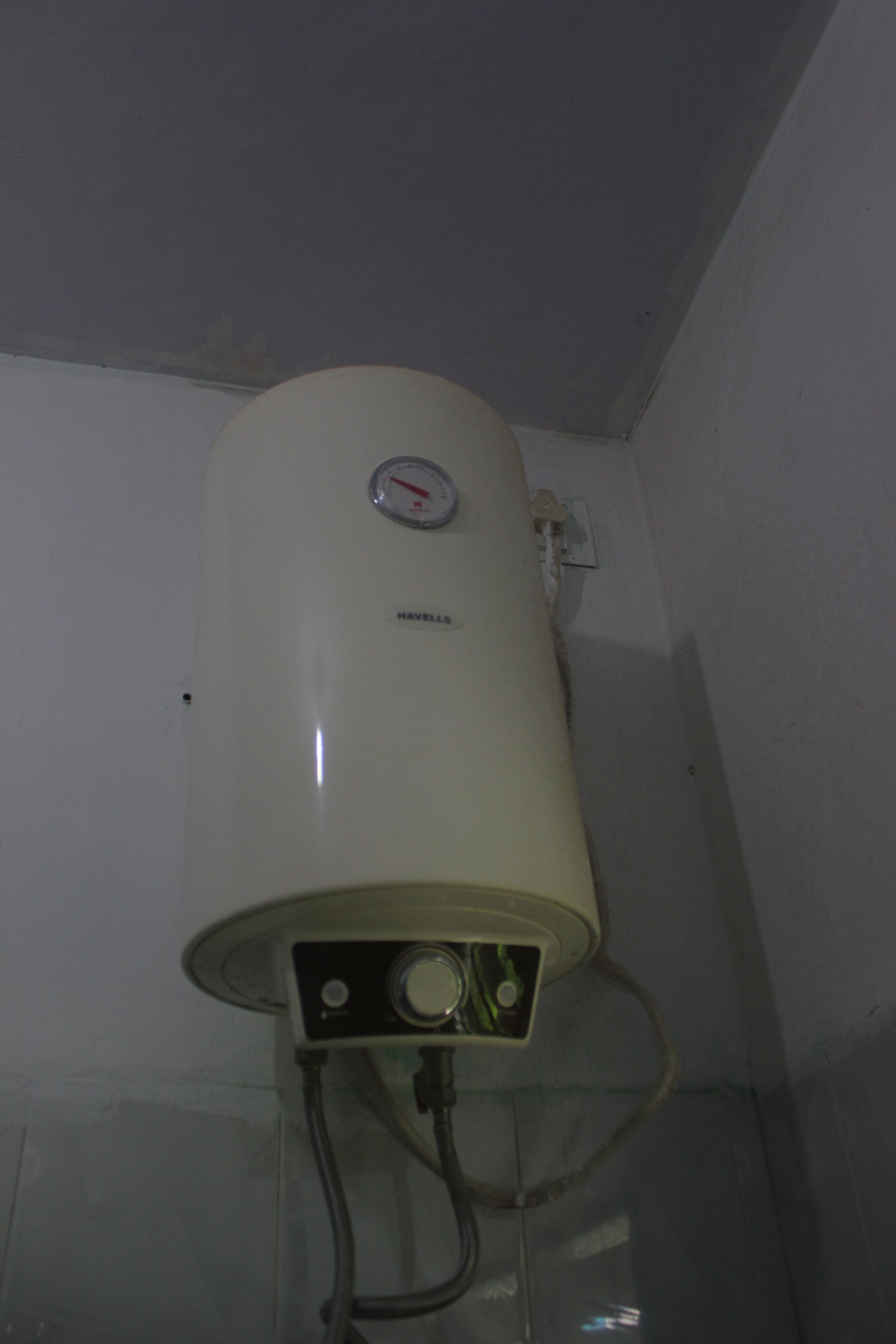 A white water heater mounted on a wall with a control panel and two visible pipes.