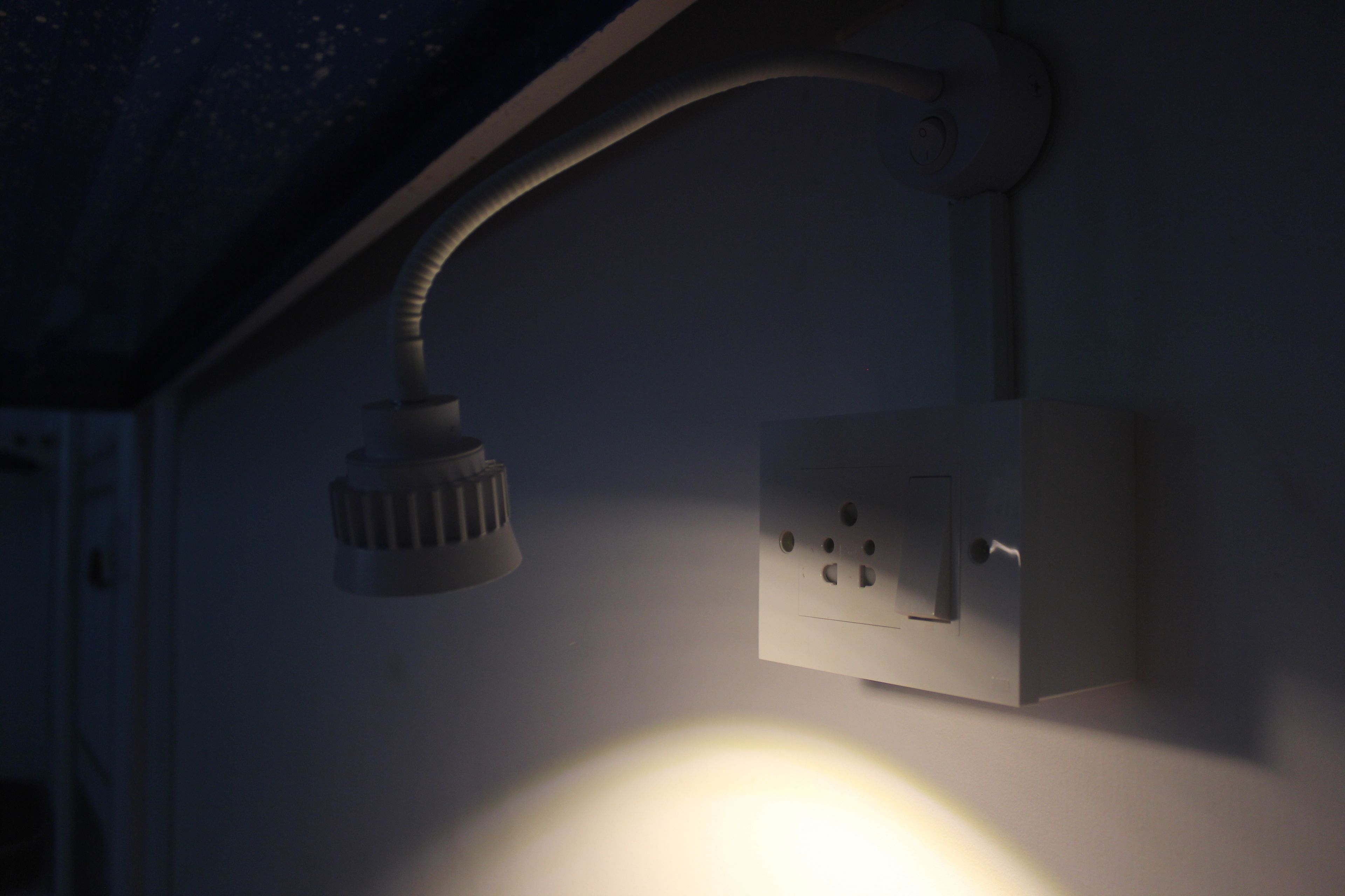 En takmonterad lampa med en böjd arm och en kopplingsdosa med flera uttag.