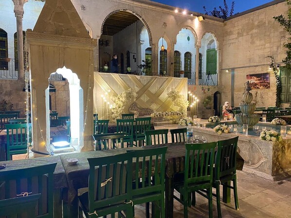 An outdoor dining area with green chairs and tables, a fountain, and arches. - Hanehan Butik Otel (Sanliurfa)